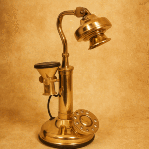 Vintage brass candlestick telephone with rotary dial on warm textured beige background